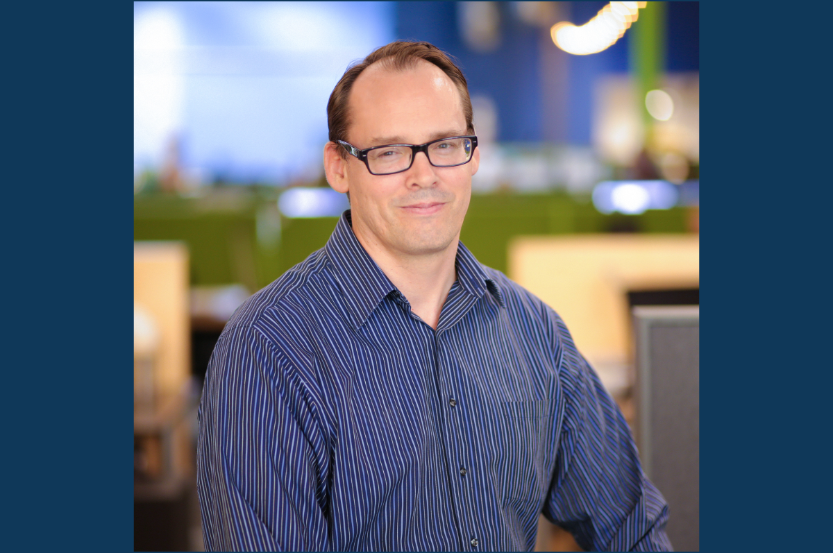 Man in blue shirt with blurred office space in background
